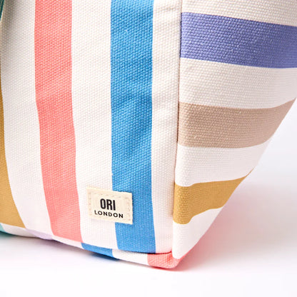 close-up of corner of Colorful striped tote with 'Ori London' label on a white background