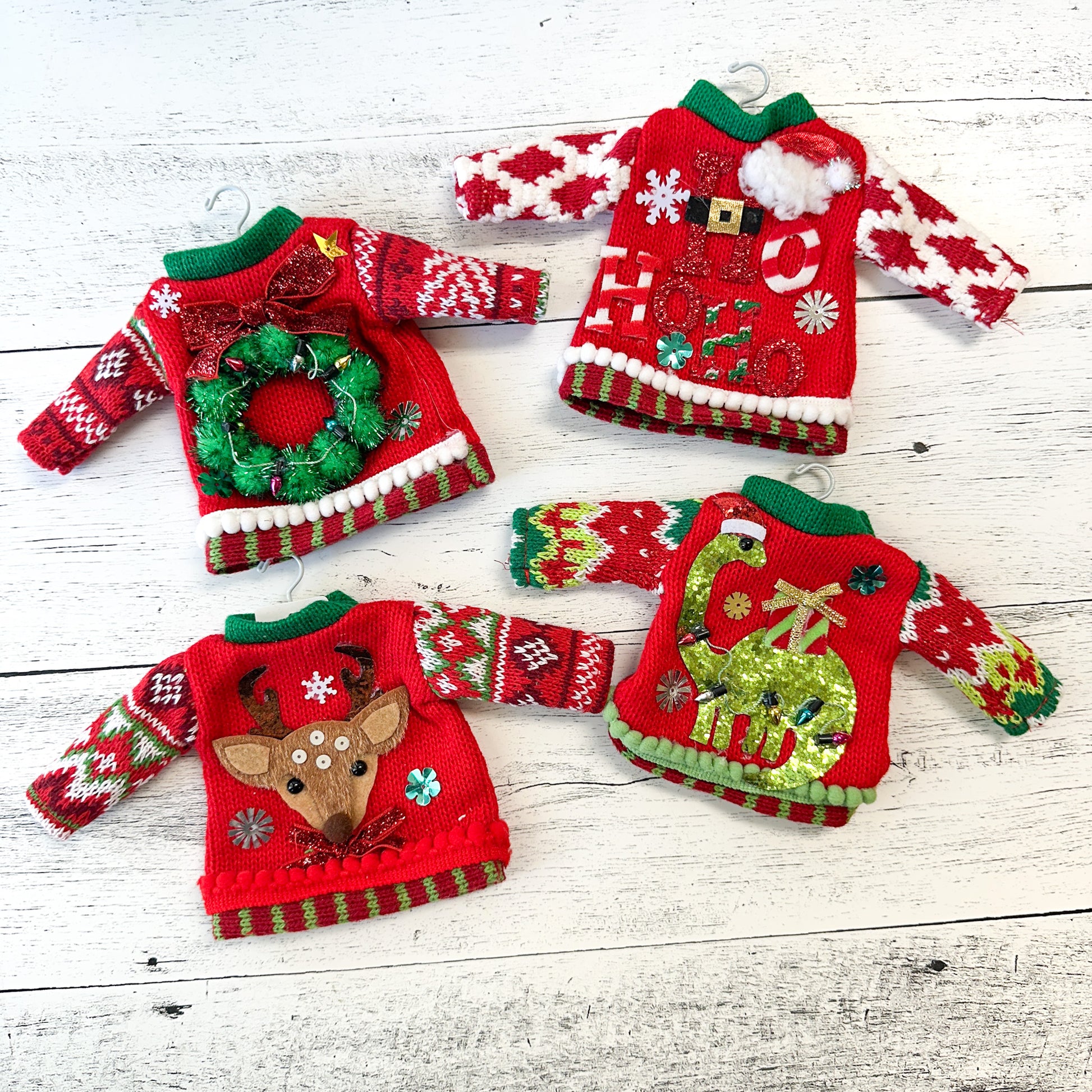 four red sweater ornaments on white hangers decorated with colorful Christmas decorations.