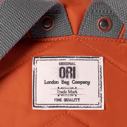 close of orange bantry b backpack's ori logo tag.