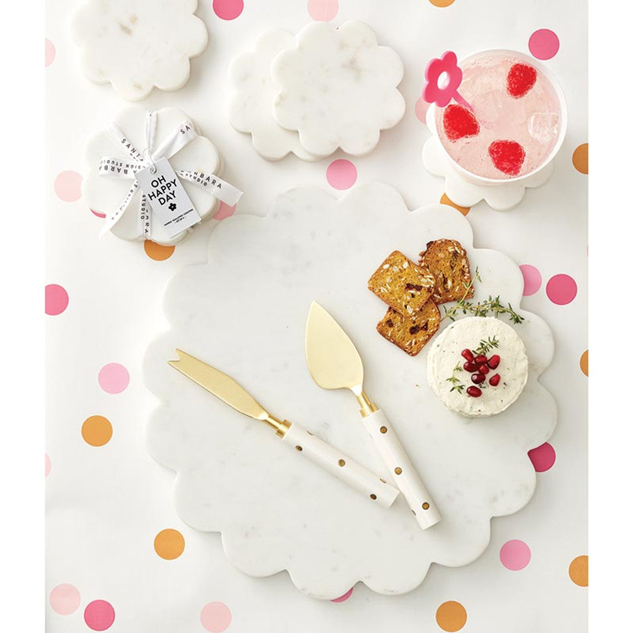 gold dot cheese knives on a marble board with cheese and crackers.