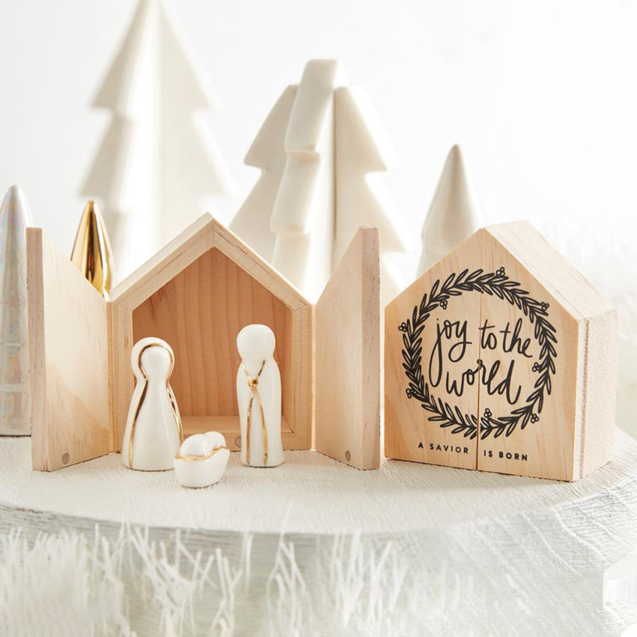 Ceramic Nativity set with wooden box arranged on a table with trees in the background