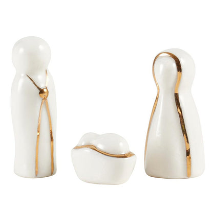 White ceramic figures of Mary Joseph and baby Jesus with golden accents arranged on a white background