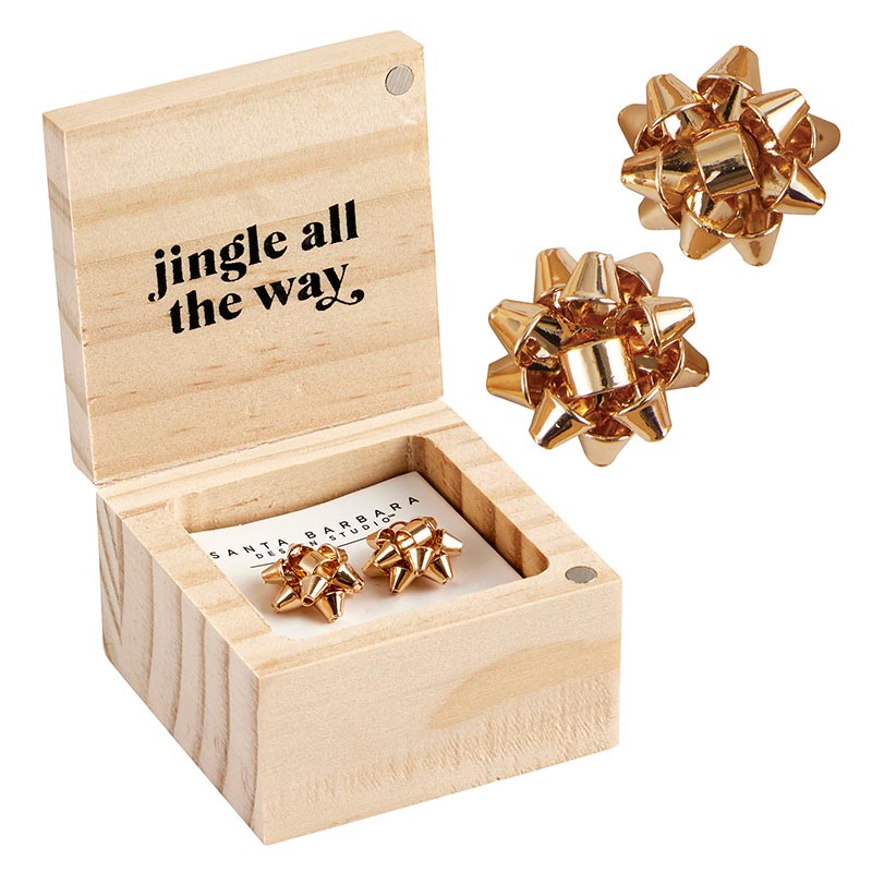 wooden box with "ingle all the way" printed in the inner lid and a pair of gold bow earrings in it and another pair of gold bow earrings displayed next to it.