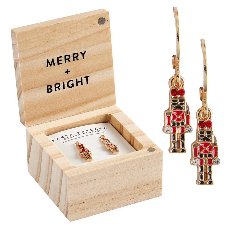 wood box with "merry + bright" printed in it and a pair of nutcracker earrings in it and another pair of nutcracker earrings displayed next to it.