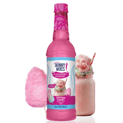 bottle of Cotton Candy skinny syrup set next to cotton candy and a glass mug of pink beverage with a blue straw in it.