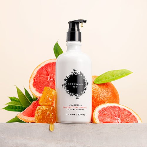 pump bottle of Honeyed Grapefruit Goat Milk Lotion arranged with grapefruit wedges and honey combs dripping with honey.