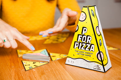 a person playing the boxed game of P for Pizza on a table