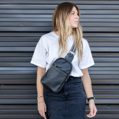 person wearing denim skirt and white tee shirt with black cass sling bag across their chest.