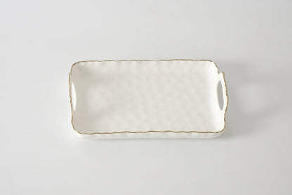 Rectangular ceramic tray with gold rim on a light gray background