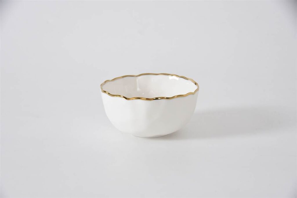 White ceramic bowl with gold rim on a light gray background