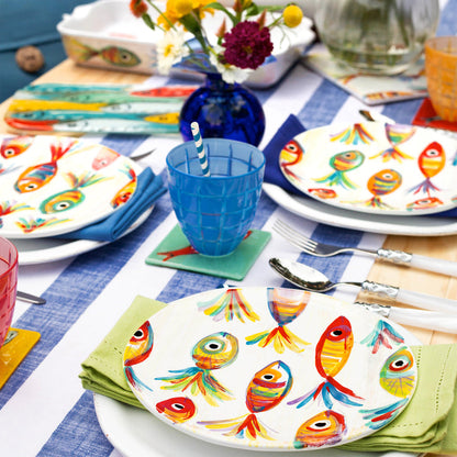 table set with white dinner plates and colorful fish salad plates, napkins, glasses, and silverware.
