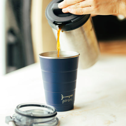 coffee being poured into a navy tumbler.