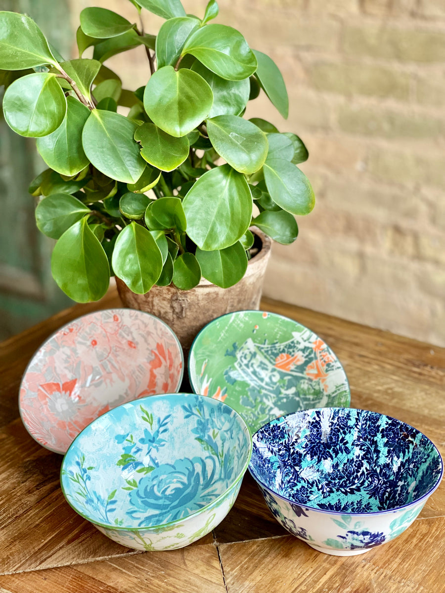4 assorted colorful bowls arranged on a table with a plant.