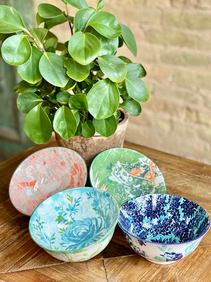 4 assorted colorful bowls arranged on a table with a plant.