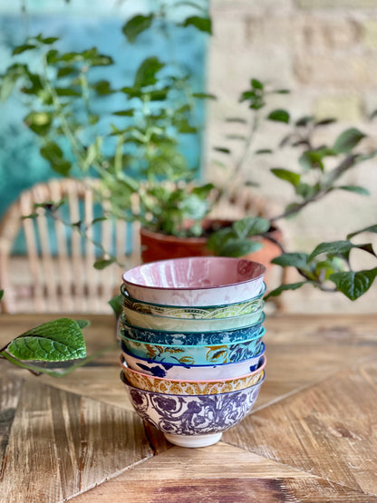 stack of 8 assorted colorful bowls on a table with greenery.