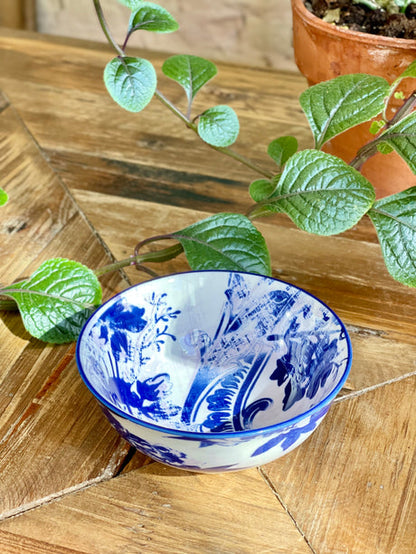 blue and white small bowl with artistic pattern on a wooden table with greenery.
