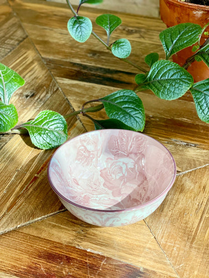 blush small bowl with artistic pattern on a wooden table with greenery.