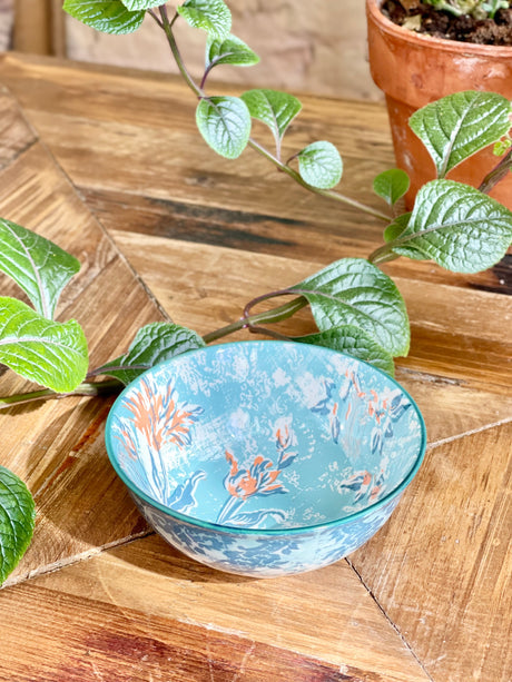blue and orange small bowl with artistic pattern on a wooden table with greenery.