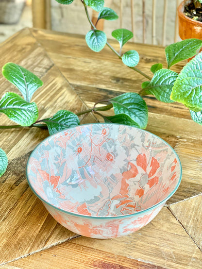 pink and orange  bowl with an artistic pattern on a wooden table with greenery.