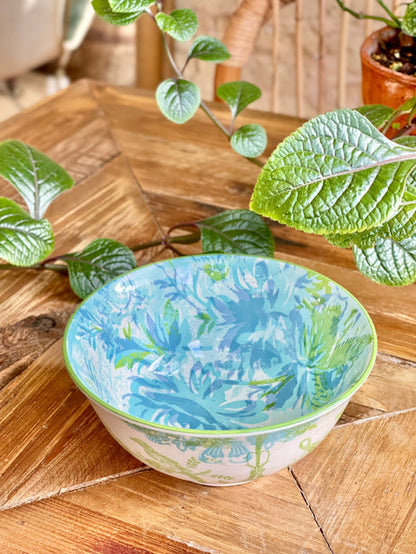blue and green  bowl with an artistic pattern on a wooden table with greenery.