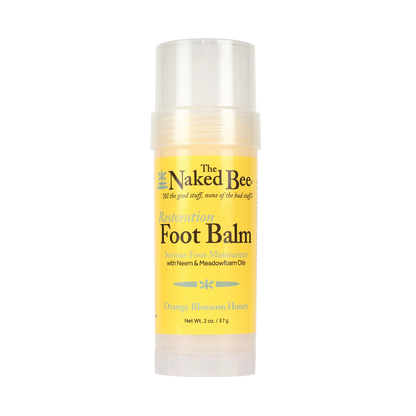 The Naked Bee Restoration Foot Balm stick in Orange Blossom Honey scent, featuring a yellow label and clear plastic cap and base, on a white background.