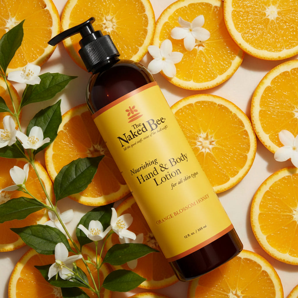 A 12 oz pump bottle of The Naked Bee Nourishing Hand & Body Lotion in Orange Blossom Honey scent, arranged on a background of orange slices and jasmine flowers