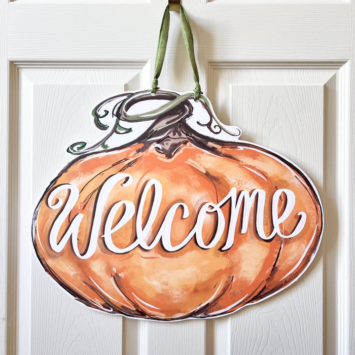 Pumpkin-shaped door sign with 'Welcome' text on a white door