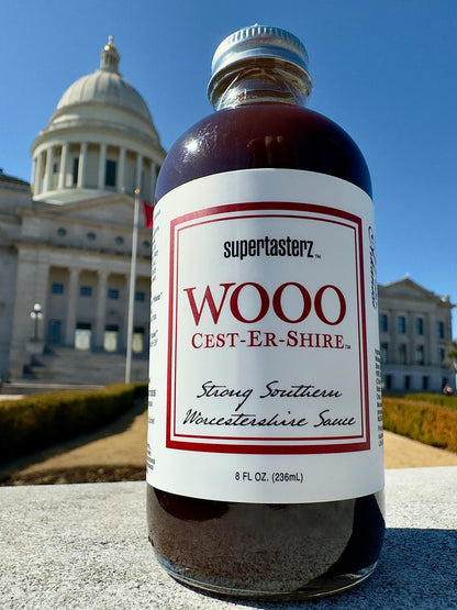 bottle of Wooo Cest-Er-Shire - Strong Southern Worcestershire Sauce pitured in front of the Arkansas state capital building in little roock