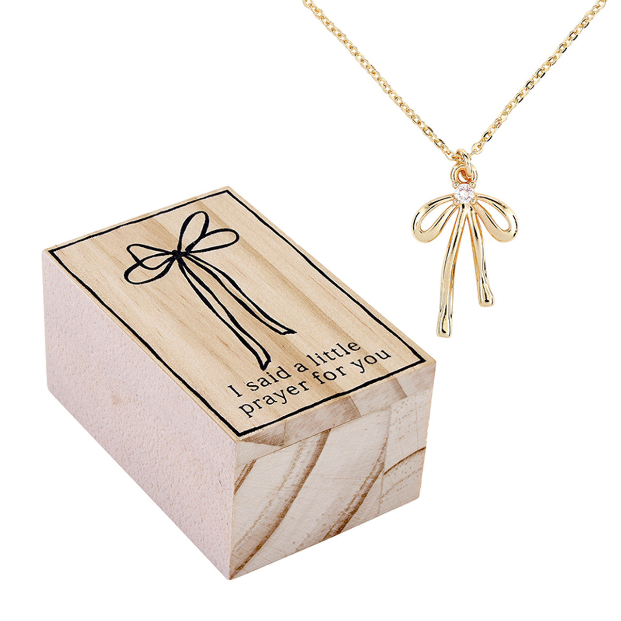 Gold necklace with bow pendant next to a wooden box with text
