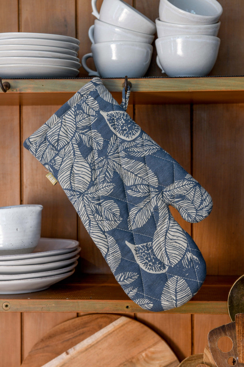 slate blue oven mitt hanging on a wooden cabinet filled with white dishes.