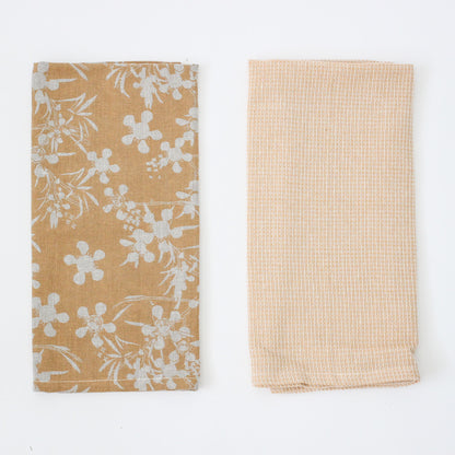 2 mustard dishtowels folded and laying next to each other on a white background.