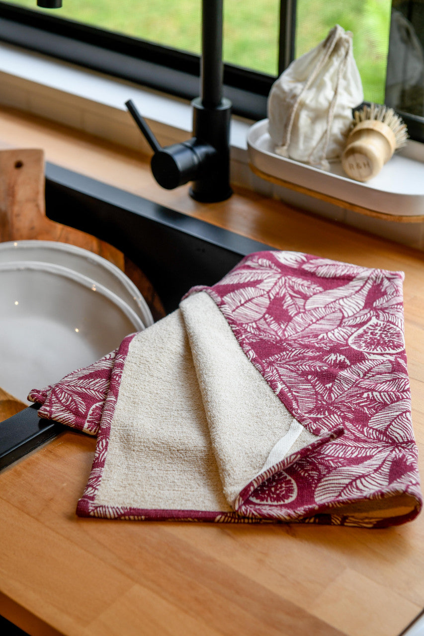 ruby dishtowel with cream terry backing draped on a kitchen counter next to the sink.