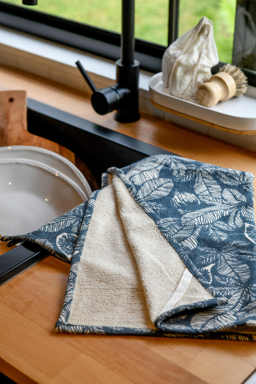 slate blue dishtowel with cream terry backing draped on a kitchen counter next to the sink.