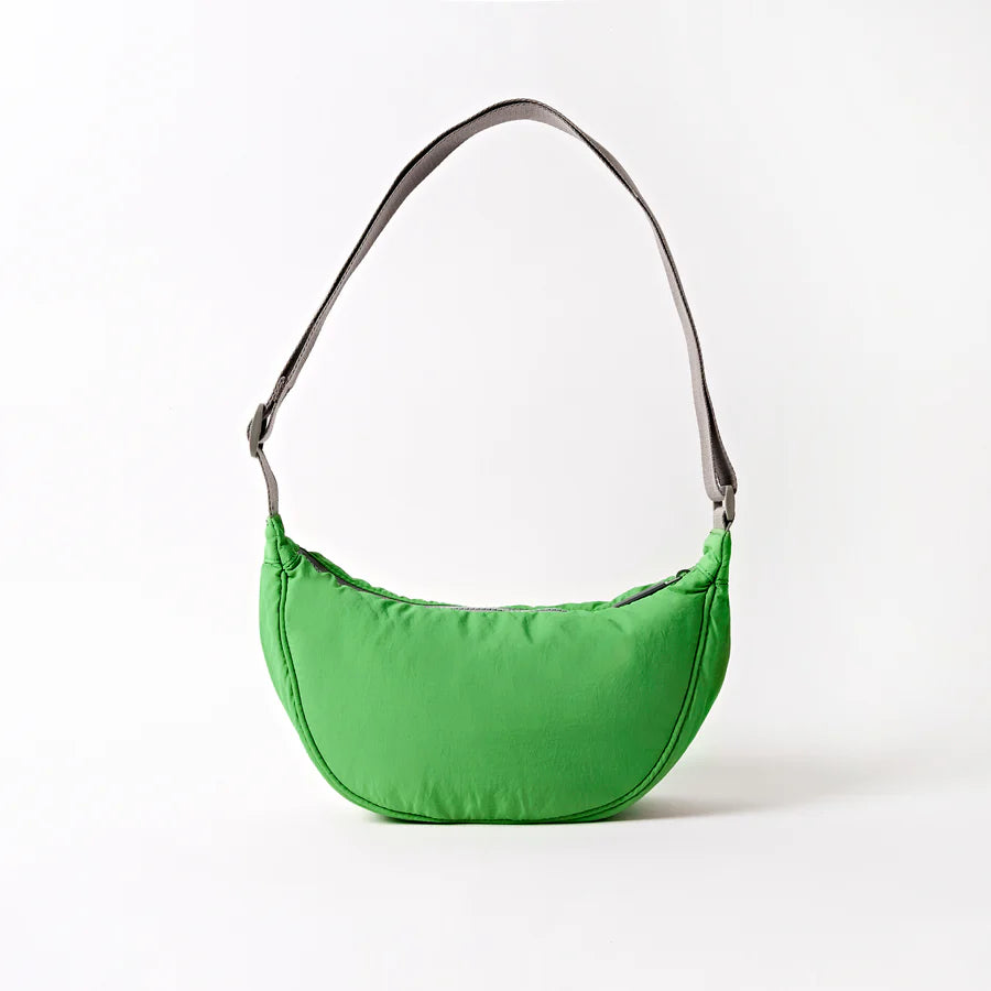 back view of green crescent shaped shoulder bag with light grey handle shown on a white background