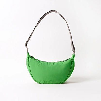 back view of green crescent shaped shoulder bag with light grey handle shown on a white background