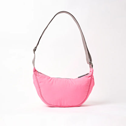 back view of pink shoulder bag with crescent shape and light grey strap shown on a white background