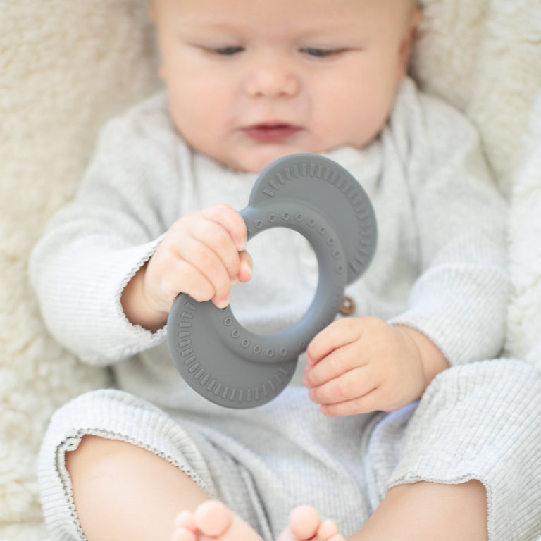 baby laying down looking at elephant teether.