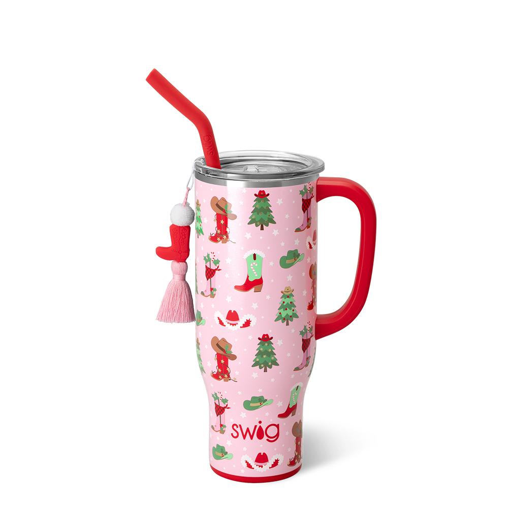 pink tumbler with red handle and straw and graphics of christmas themed boots and cowgirl hats and christmas trees.