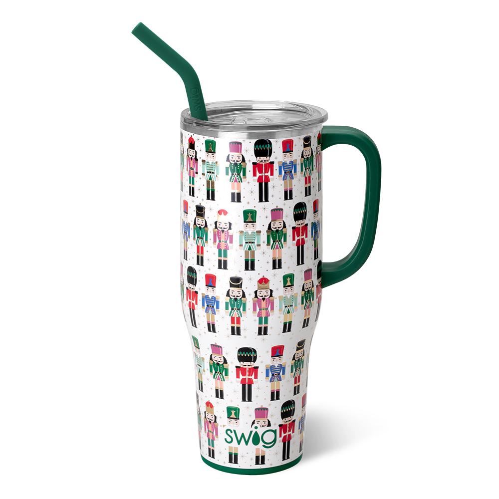 white tumbler with green handle and straw and nutcrackers in colorful uniforms all over it.