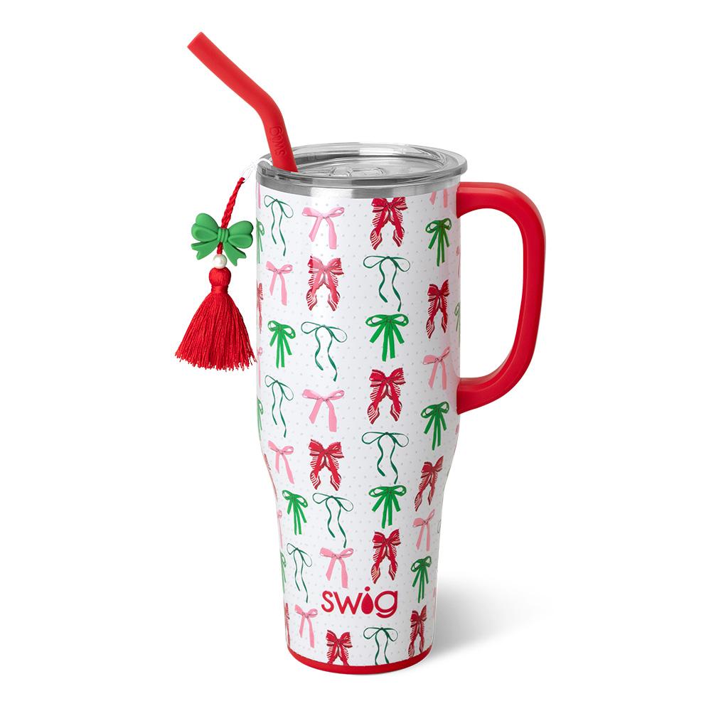 white tumbler with all-over bow design, red handle and straw, and red tassel hanging on it.