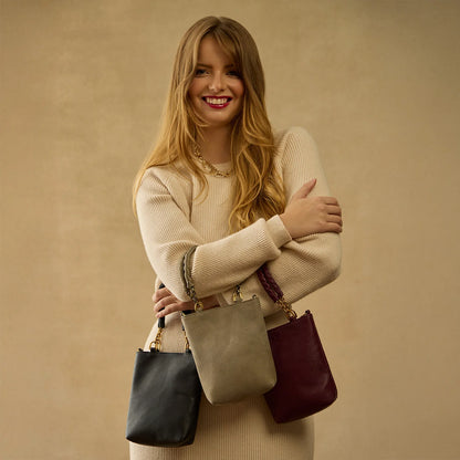 smiling person wearing beige sweater and holding 3 assorted Tennessee Mini Bags