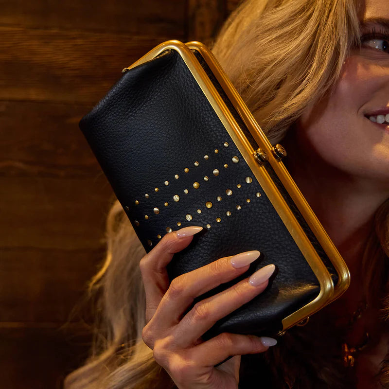 smiling person holding Lauren Clutch Wallet in black with gold studs