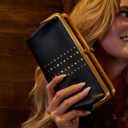 smiling person holding Lauren Clutch Wallet in black with gold studs