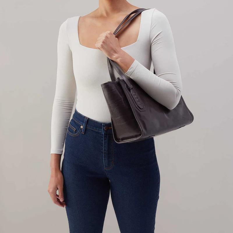 model holding the expedition small tote bag in the color flintrock on her shoulder