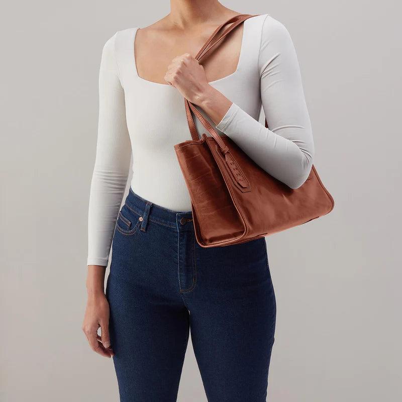 model wearing the expedition small tote bag in the color pecan ridge over a shoulder