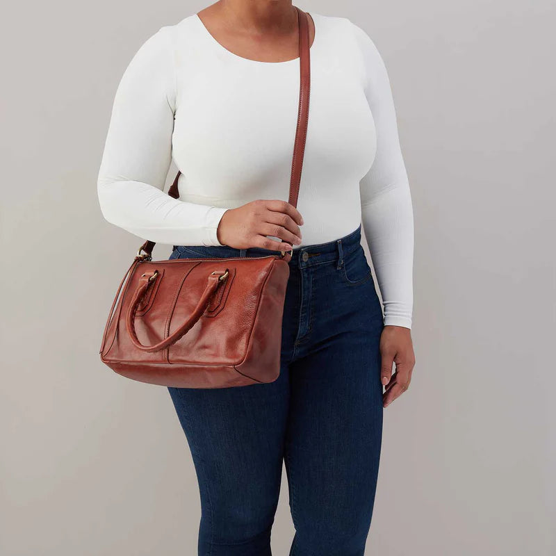 model wearing the expedition satchel in the color pecan ridge as a crossbody