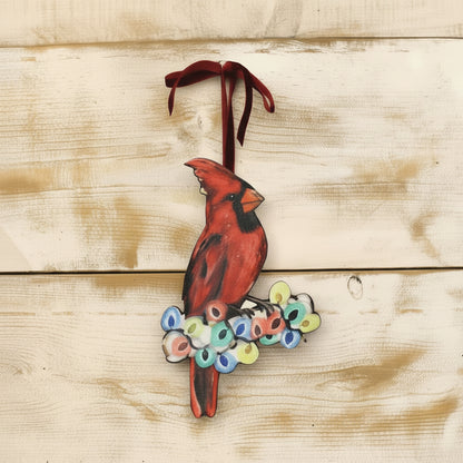 flat ornaments of a cardinal sitting on a branch covered in christmas lights