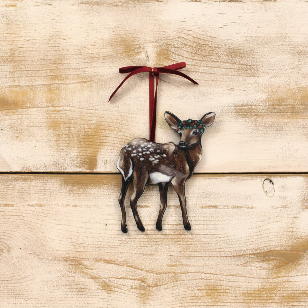 deer ornament wearing a holly crown against a wood background