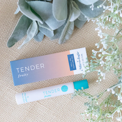 Perfume oil packaging with 'Tender' branding on a textured surface with plants.