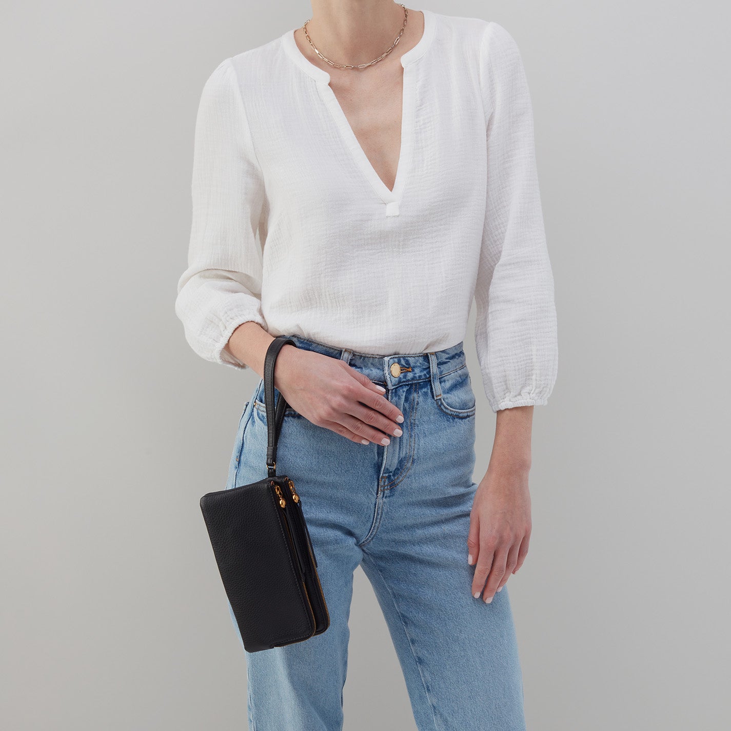 woman wearing white blouse and jeans with black  Dayton Wristlet hanging on her wrist.